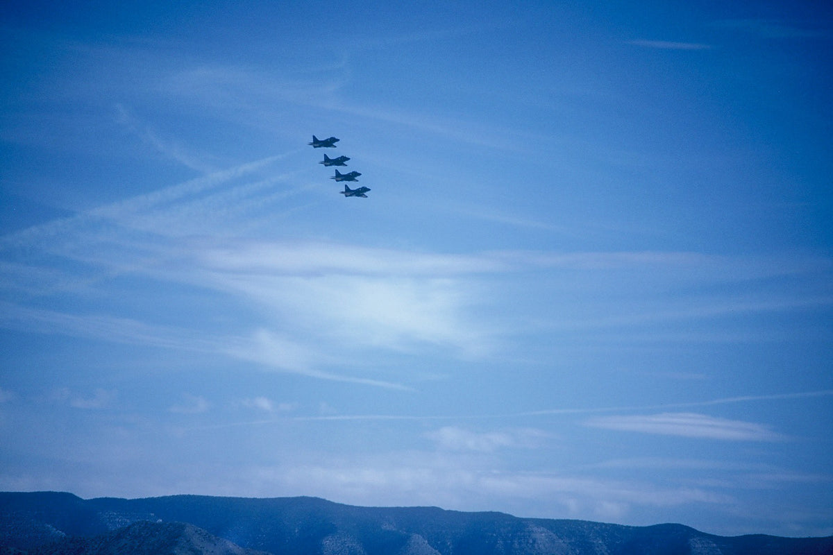 Four jets fly in close formation above mountains at an air show in Albuquerque.