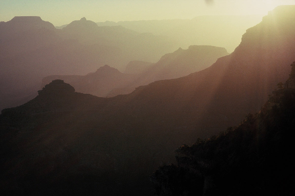 Successive Grand Canyon ridges fade into golden haze as sunlight enters from the upper right.