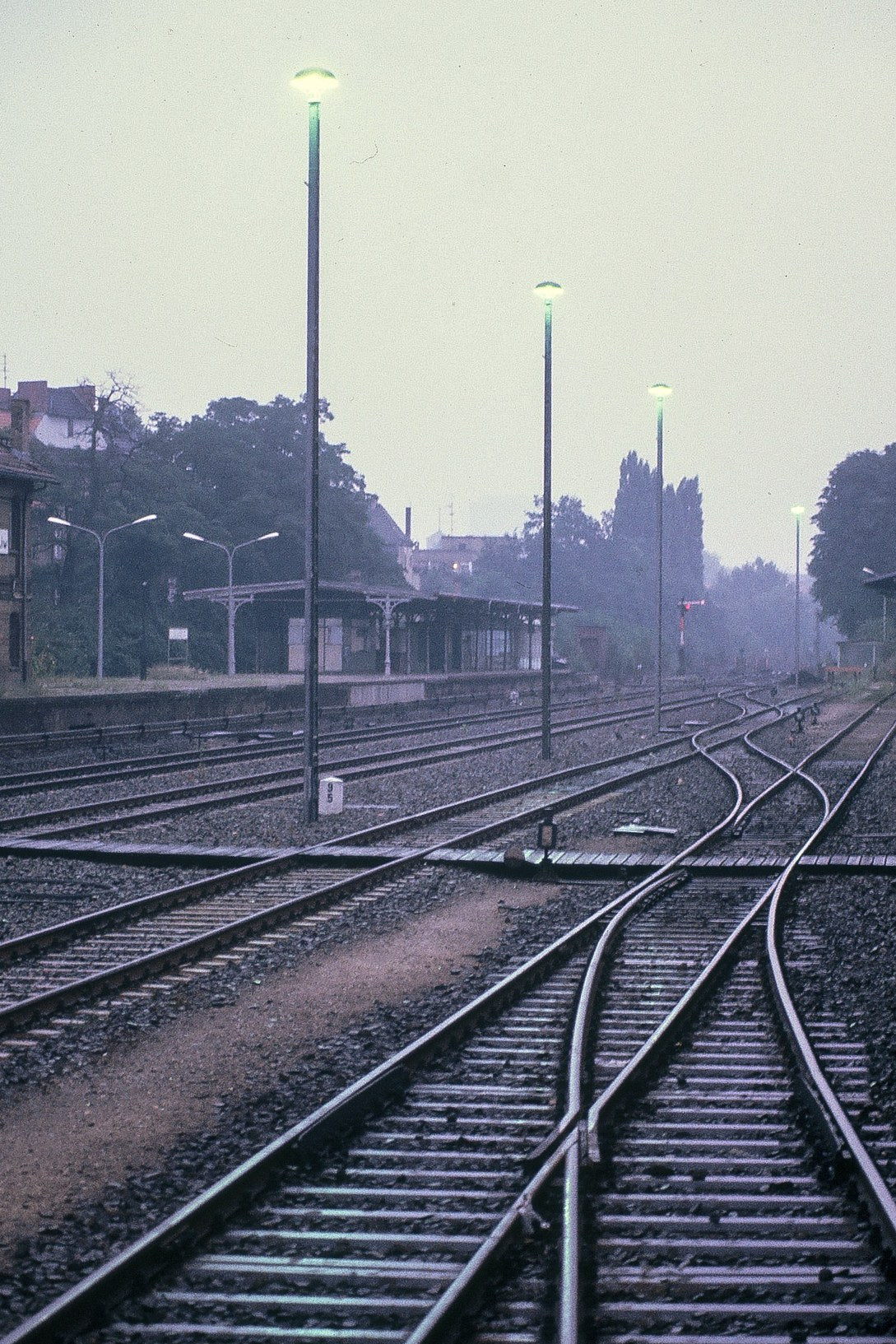 Railway tracks converge beneath tall lamps in an East Berlin rail yard.